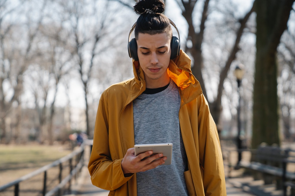 teen-boy-walking-in-a-park-with-headphones